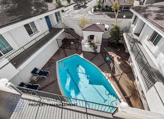 A pool surrounded by apartment buildings with a sign for beach property management.