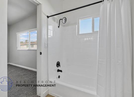 A white bathroom with a shower curtain and a window.
