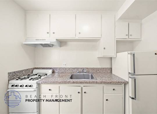 A kitchen with a stove, sink, and cabinets.