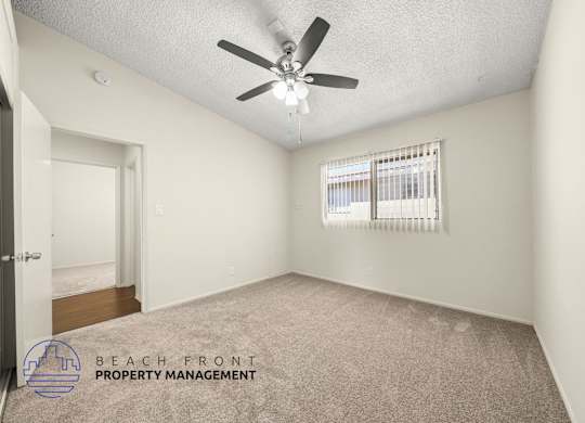 A room with a ceiling fan and a window with blinds.