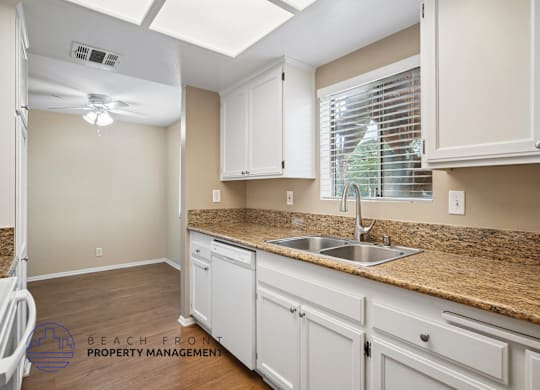 A kitchen with white cabinets and a granite countertop.