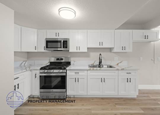A kitchen with white cabinets and a stove top oven.
