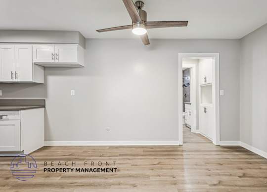 A room with a ceiling fan and wooden flooring.