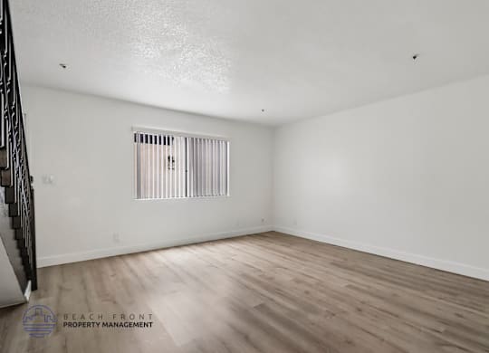 A room with wooden flooring and a window with blinds.
