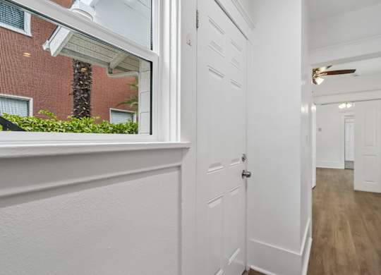 A white door is in a hallway with wood floors.