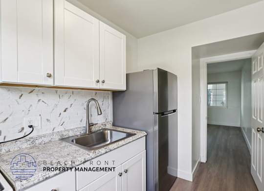 A kitchen with a sink and refrigerator with a logo for Beachfront Property Management.