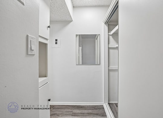 A white hallway with a door on the left and a window on the right.