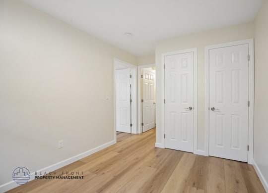 A room with white doors and wooden floors.