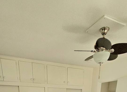 A room with a ceiling fan and wooden flooring.