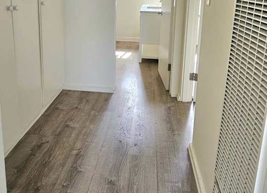 A long hallway with wood floors and white walls.