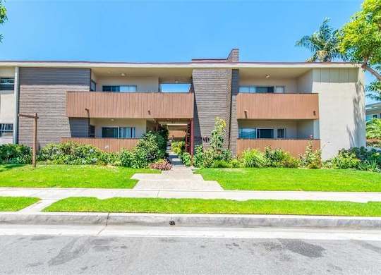 A modern two-story building with a brown and beige exterior and a green lawn in front.