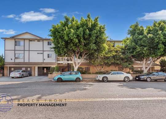 A parking lot with cars and a building with the words Beach Front Property Management.