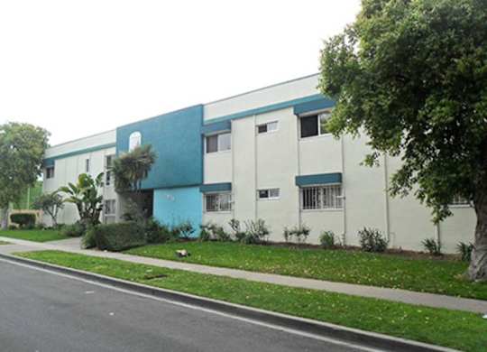 A blue and white building with a tree in front.