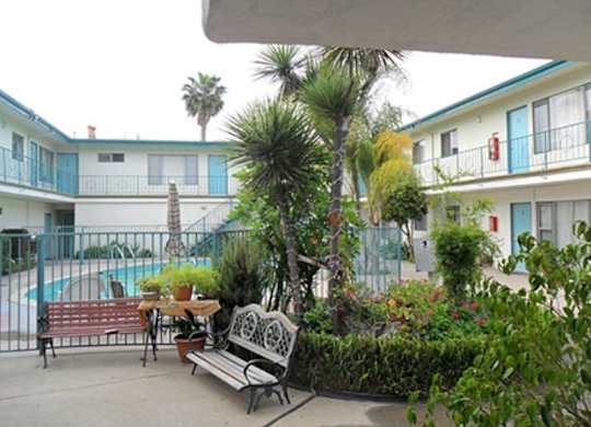 A patio with a table and chairs overlooks a pool.