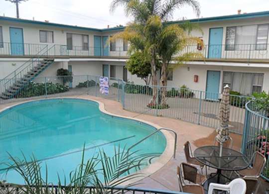 A pool surrounded by chairs and a fence.