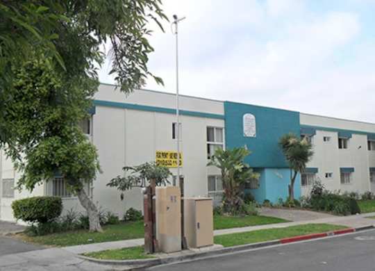 A building with a blue and white exterior has a sign that says