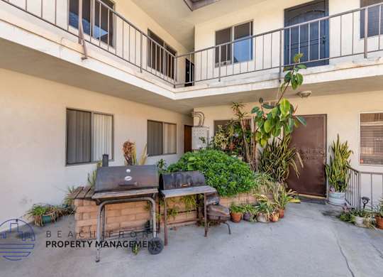 A balcony with a grill and potted plants.
