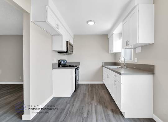 A kitchen with white cabinets and a wooden floor.