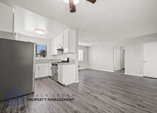 A spacious kitchen with white cabinets and a wooden floor.