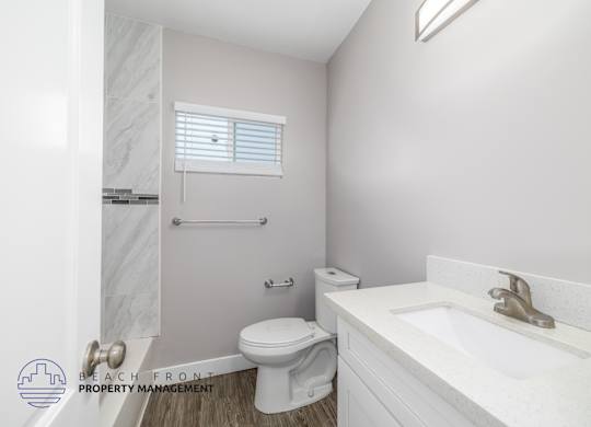 A white bathroom with a toilet, sink, and a window.