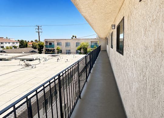 A long concrete walkway with a black railing on the left side and a building on the right side.