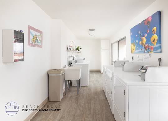 A clean, white-walled office space with a desk, chairs, and a large painting on the wall.