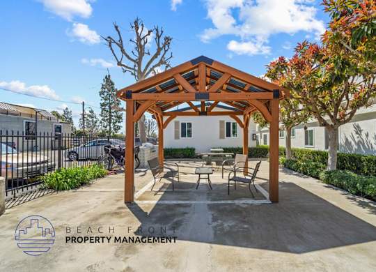 a patio with a picnic table and chairs under a wooden pavilion