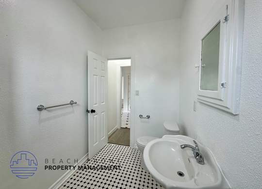 A bathroom with a white sink and a black and white floor.
