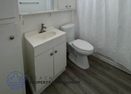 A white bathroom with a toilet, sink, and shower curtain.