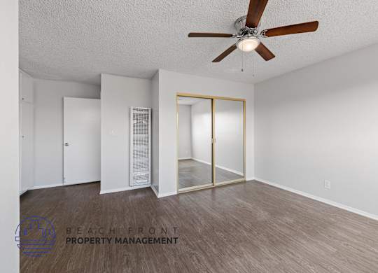 the spacious living room of an apartment with a ceiling fan