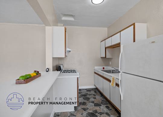 A kitchen with a refrigerator, sink, stove and cabinets.