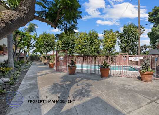 A pool surrounded by a fence and potted plants.
