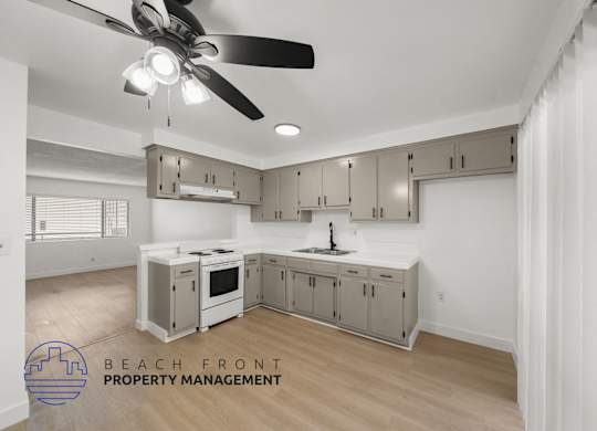 A kitchen with a ceiling fan and a logo for Beach Front Property Management.