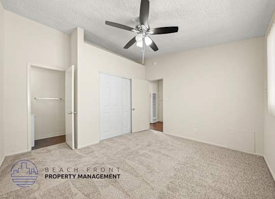 A spacious room with a ceiling fan and carpeted floor.