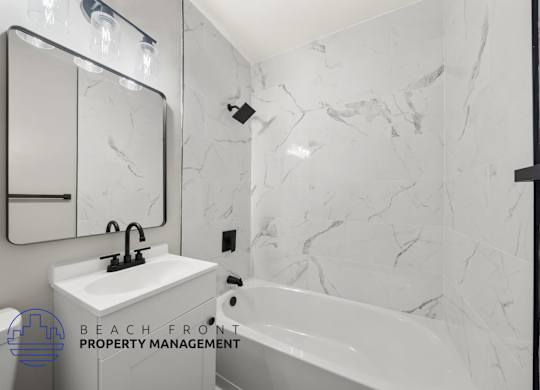 A bathroom with a marble wall and a white sink.