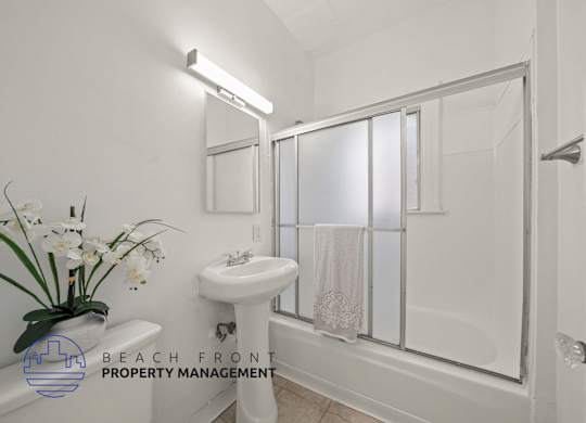 A white bathroom with a sink, mirror, and shower.