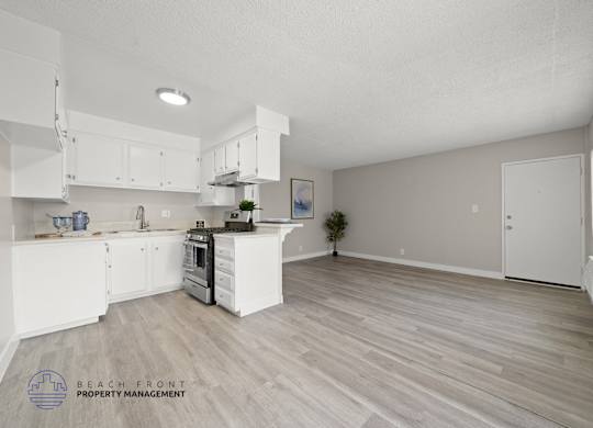 A spacious kitchen with white cabinets and a wooden floor.