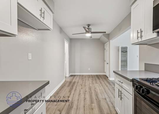 A kitchen with a stove top oven and a fan on the ceiling.