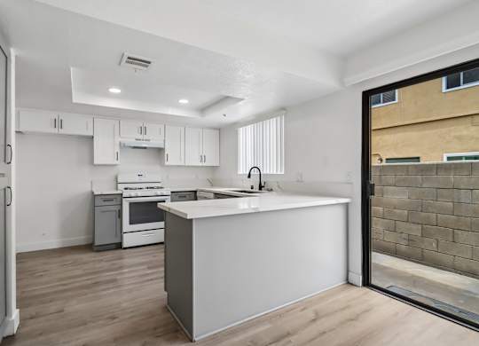 A modern kitchen with white cabinets and a wooden floor.