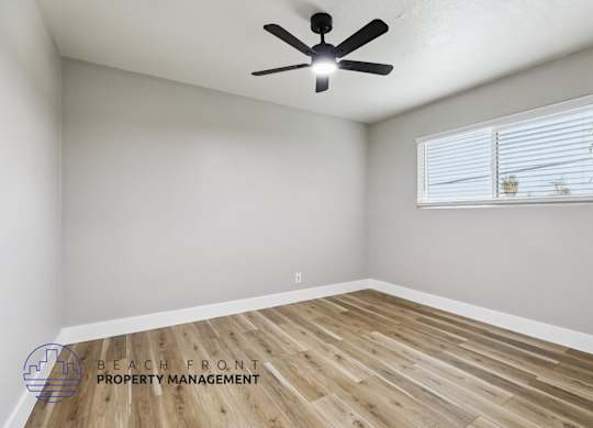 A room with a ceiling fan and wooden flooring.