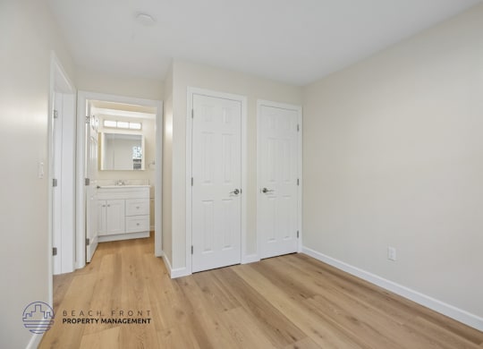 A white bedroom with a dresser and a mirror.