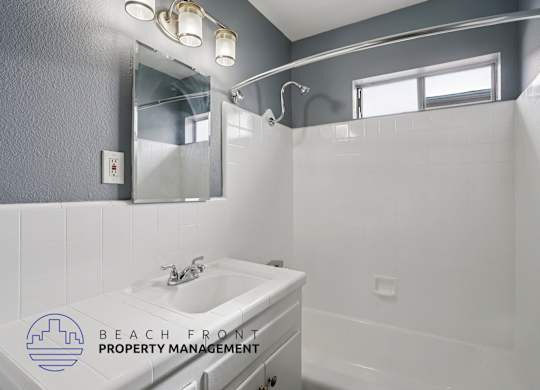 A bathroom with a sink, mirror, and a window.
