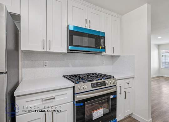 A kitchen with white cabinets and a blue microwave.