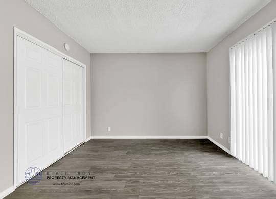 A room with a white door and a window with white blinds.