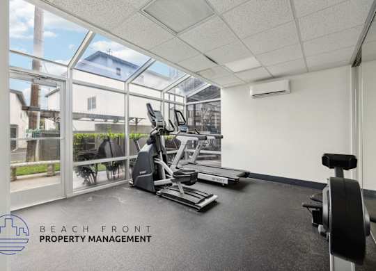 A gym room with a view of the outside through the windows.