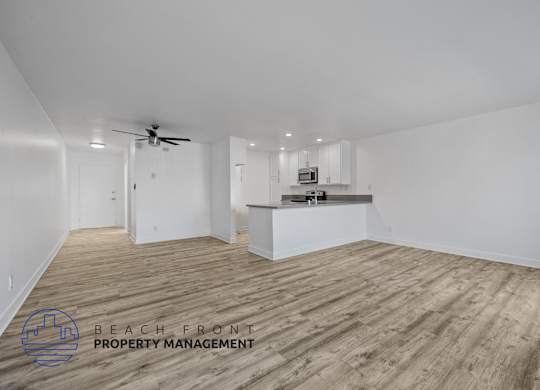 A spacious room with wooden flooring and a ceiling fan.