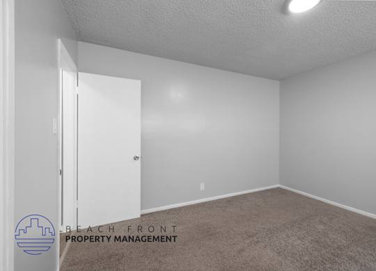 the spacious living room of an apartment with white walls and carpet