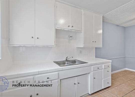 A kitchen with white cabinets and a sink.