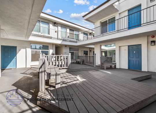 A balcony with a table and chairs is on the second floor of a building.
