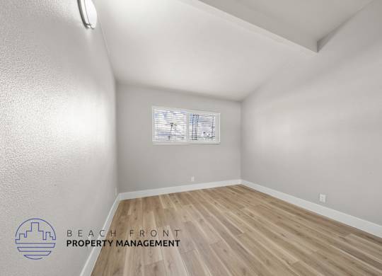 A room with wooden flooring and a window with blinds.